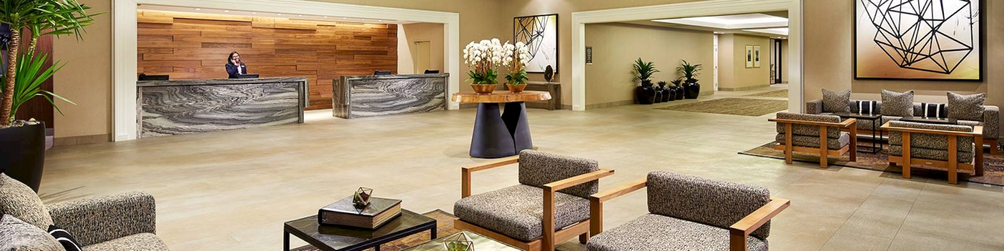 A spacious and modern hotel lobby features seating areas, a reception desk, and contemporary decor.