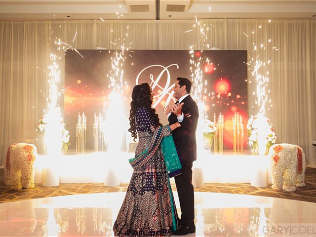 A couple dances amid sparklers at a decorated event, with flowers and drapes enhancing the elegant atmosphere.