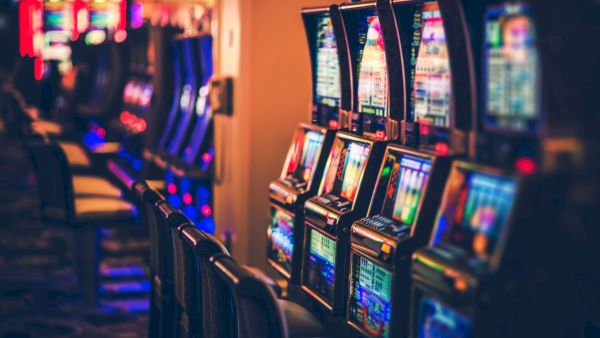 The image shows a row of colorful slot machines in a casino setting.