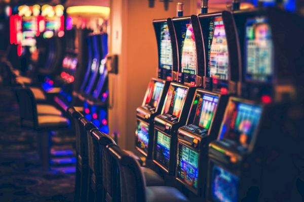 The image shows a row of colorful slot machines in a casino setting.