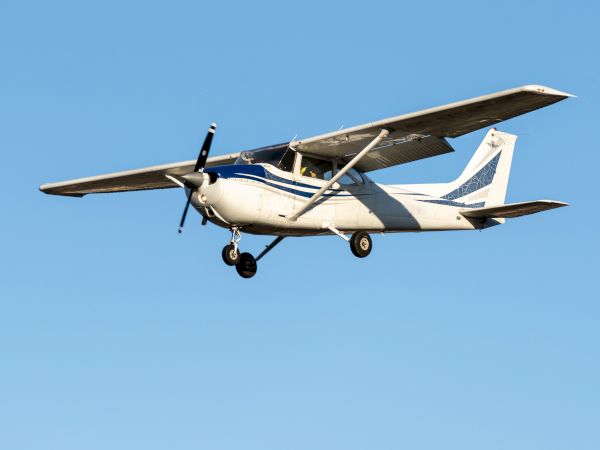 A small single-engine airplane is flying in a clear blue sky, with its landing gear extended.