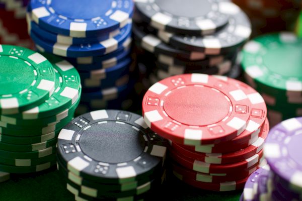 Stacks of colorful poker chips in red, blue, green, black, and purple piled on a felt surface.