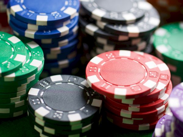 Stacks of colorful poker chips in red, blue, green, black, and purple piled on a felt surface.