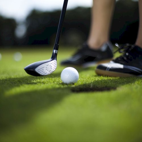 A person stands on a golf course, preparing to hit a golf ball with a club.