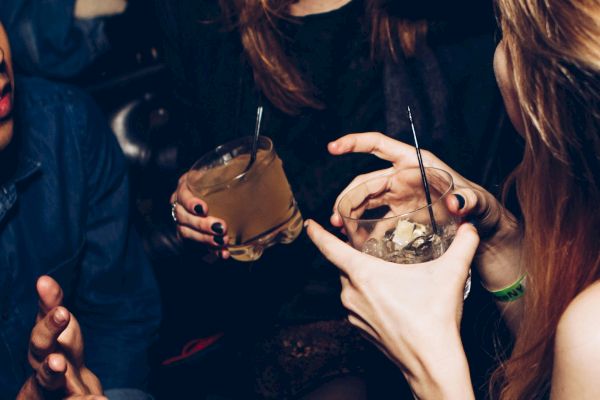 People socializing with drinks in hand, laughing and expressing themselves in a lively setting.