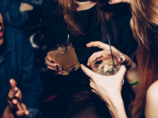 People socializing with drinks in hand, laughing and expressing themselves in a lively setting.