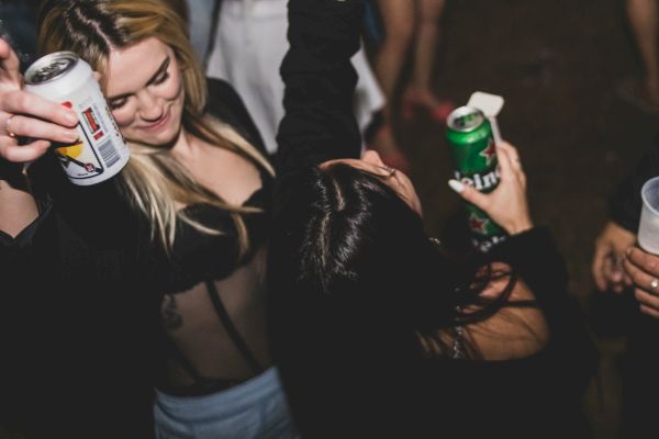 Two people are enjoying a lively party, holding drinks and dancing with energy and enthusiasm.