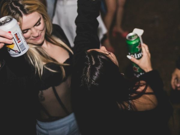 Two people are enjoying a lively party, holding drinks and dancing with energy and enthusiasm.