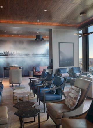 A modern lounge with comfortable seating, large windows offering a scenic view, and cityscape artwork on the wall in a cozy ambiance.